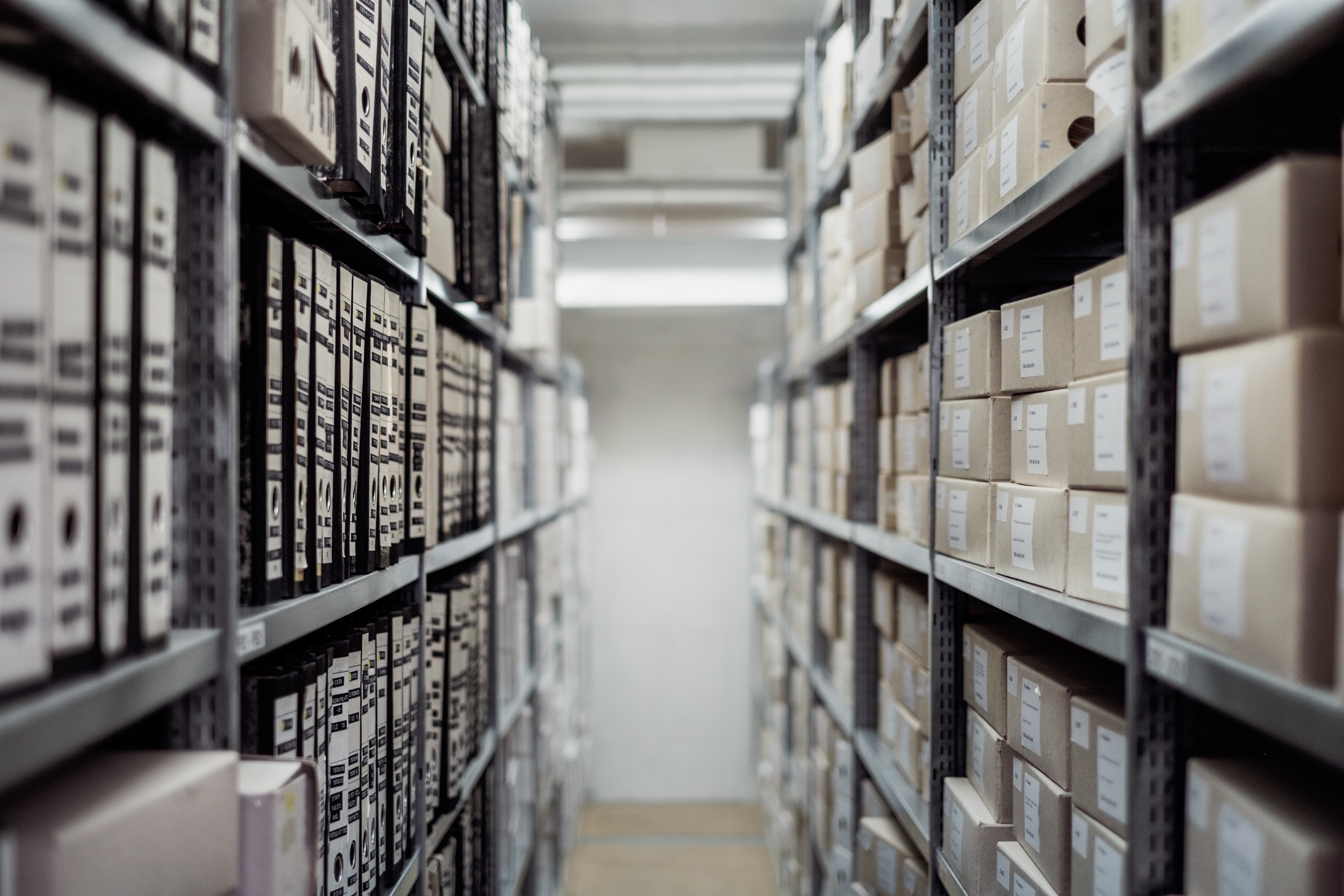 Rows of rolling archive shelves filled with files along a narrow aisle.